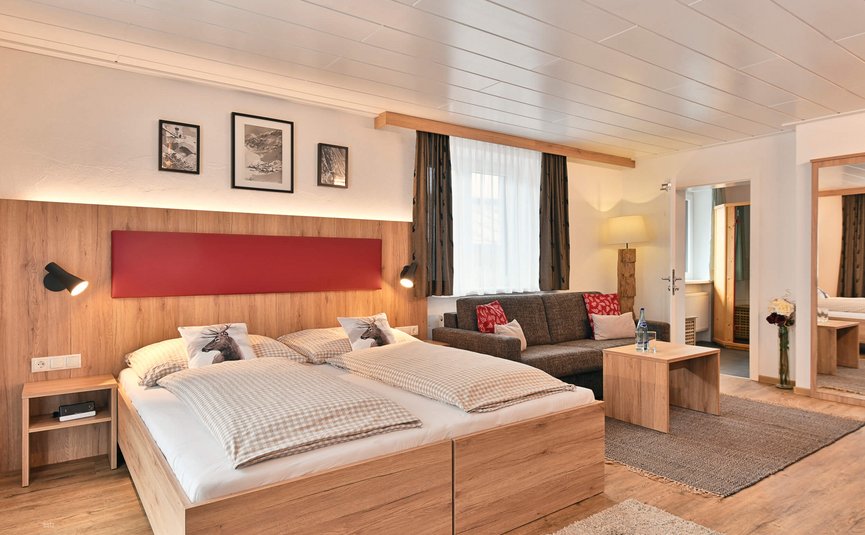 Gemütliches Schlafzimmer mit Doppelbett, Sofa und Holzmöbeln