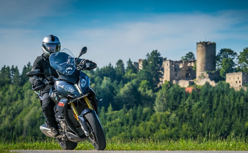 Motorradurlaub im Mühlviertel © Moppetfoto.de Motorradfahrer auf Landstraße vor bewaldetem Hügel mit Burgruine