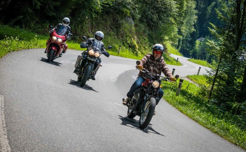 Biker Week Drei Motorräder fahren auf einer kurvigen Landstraße im Grünen