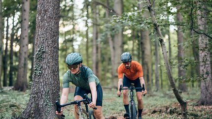 GravelBikeGlück @Slowenien © Tobias Köhler Zwei Radfahrer fahren durch einen Wald auf einem schmalen Pfad