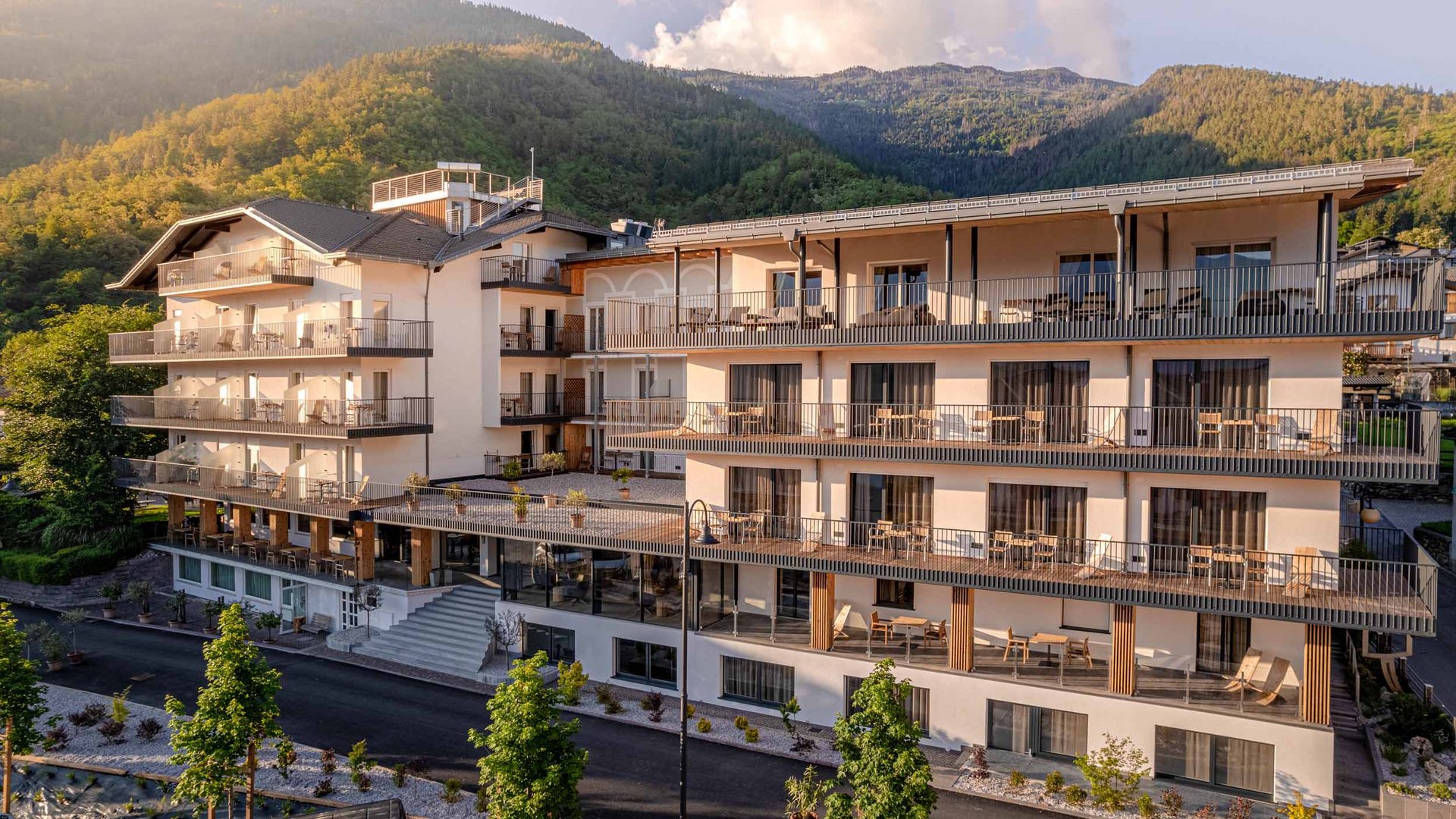 So geht Gravelbike-Urlaub im Hotel Cristallo
 © Andrea Acler Modernes Hotelgebäude vor bewaldeten Bergen im Sonnenlicht