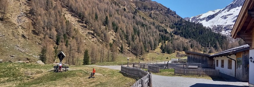Berglandschaft mit Fahrradfahrern und einem Haus im Tal