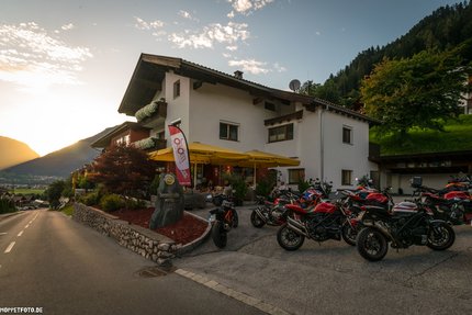 Hotel mit Motorrädern auf Parkplatz bei Sonnenuntergang in den Bergen