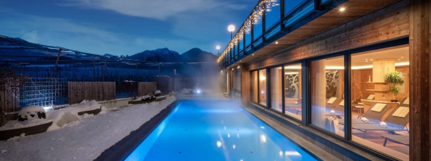 Jonathan´s Winter Wohlfühlwochen 7=6 Beheiztes Außenpool bei Nacht neben einem modernen Spa mit Bergblick