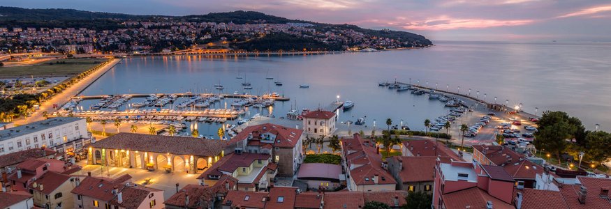 Abendlicher Blick auf Hafen und Stadt mit beleuchteten Gebäuden am Wasser
