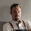 Motorradurlaub in Kärnten © Ramona Steiner Mann mit Kochschürze und verschränkten Armen vor weißer Wand