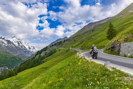Motorradurlaub im Mölltal – Großglockner – Nockalm © Alexander Seger Motorradfahrer auf kurvenreicher Bergstraße mit grünen Wiesen und schneebedeckten Gipfeln