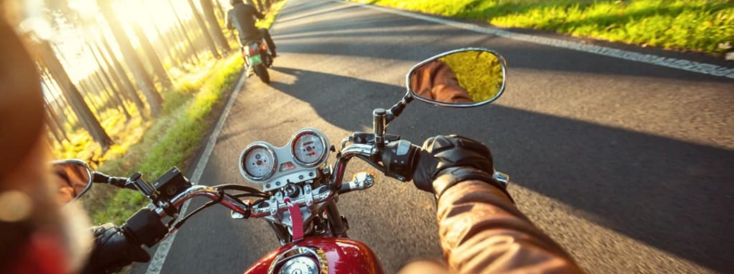 Dolomiti Motorbike Days Motorradfahrer fährt auf Landstraße im Sonnenlicht