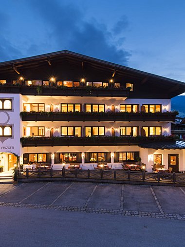 Beleuchtetes Hotelgebäude am Abend in den Bergen