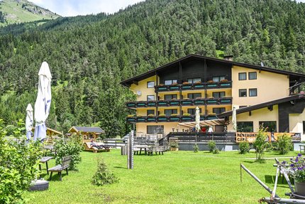 Schönauer Hof © Schönauer Hof - Porsche Gelbes Alpenhotel mit Garten vor bewaldetem Berg im Sommer