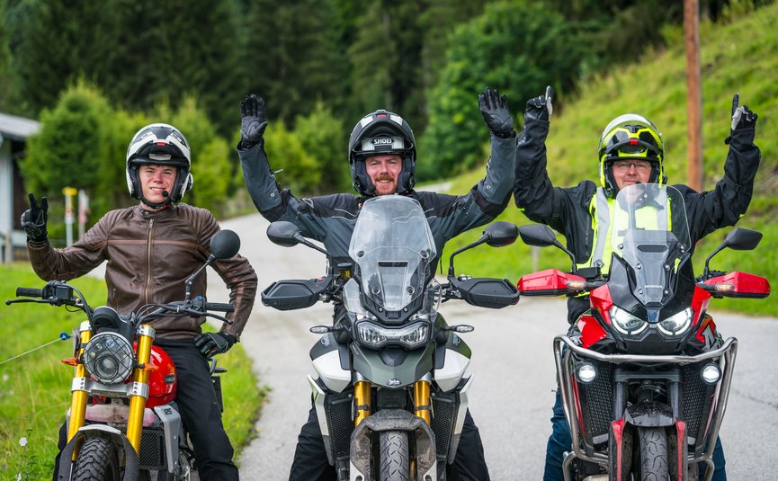 Drei Motorradfahrer in Schutzkleidung und Helmen auf einer Landstraße