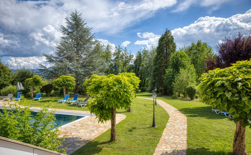 Hotel Marienhof – mein Refugium **** © Bianca Wagner Garten mit Pool, Liegestühlen und Weg unter einem bewölkten Himmel