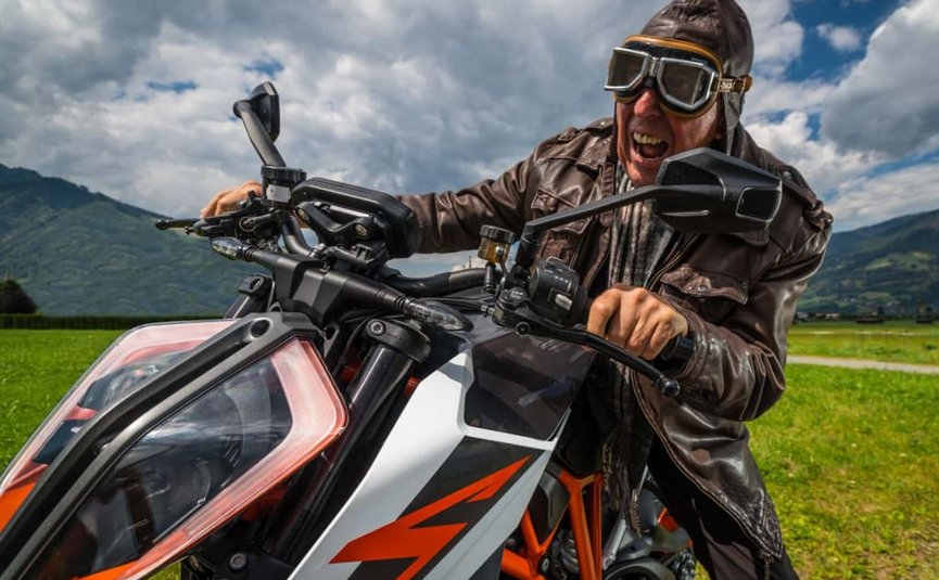 Kurvenkönig Special ab € 208,- pro Person Mann in Lederjacke und Schutzbrille auf Motorrad in ländlicher Landschaft