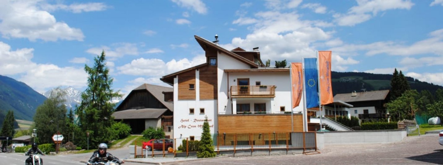 Moar's Bike & Relax Week Straße mit Motorrädern vor einem Hotel in einer Alpenlandschaft