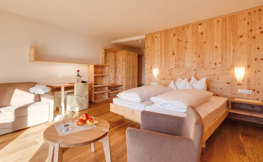 Helles Holz-Schlafzimmer mit Doppelbett und gemütlicher Sitzecke