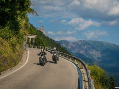 Friaul – Karnien © Moppetfoto.de Zwei Motorradfahrer auf kurviger Bergstraße mit Bergen im Hintergrund.