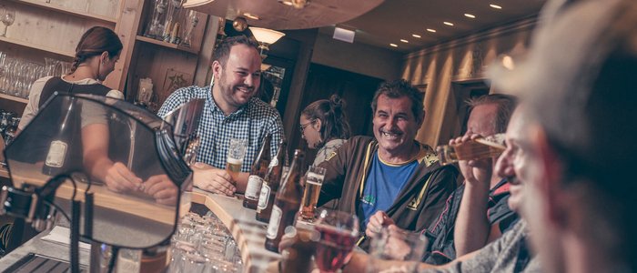 Menschen sitzen lachend und trinkend an einer Bar
