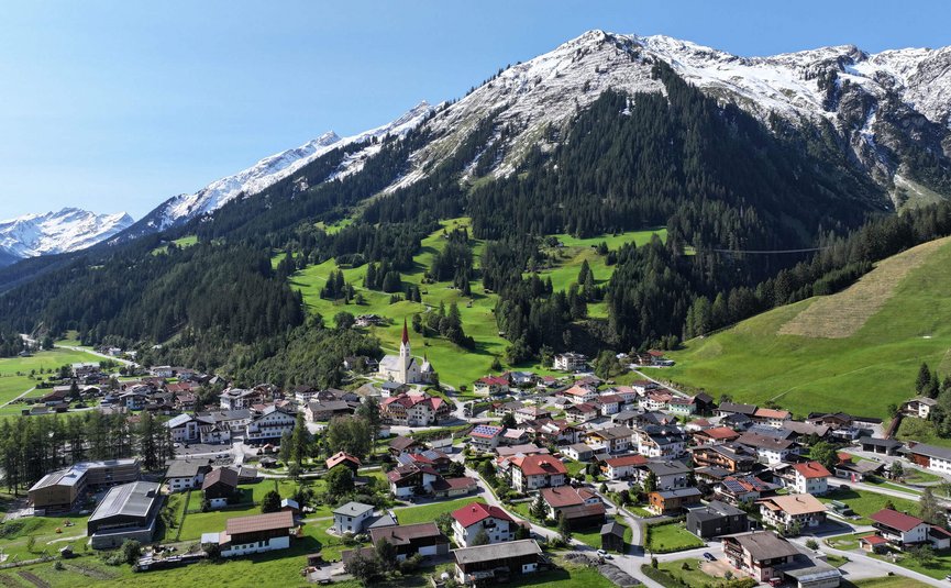 Dorf vor schneebedeckten Bergen unter klarem Himmel