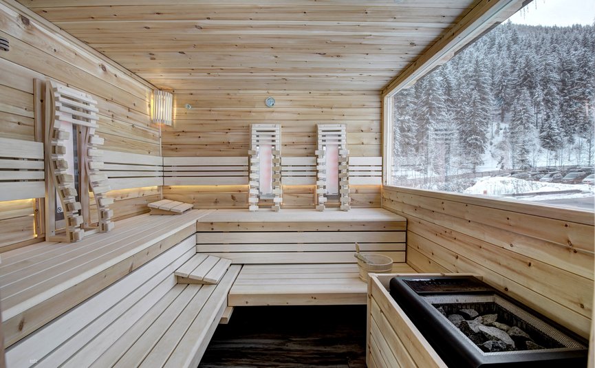 Sauna mit Holzinterieur und Panoramafenster auf verschneiten Wald