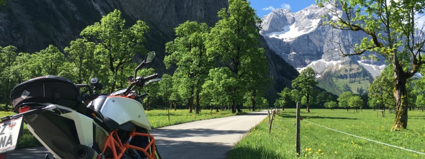4 Tage Motorradfahren im Zillertal Motorrad an Landstraße mit grünen Bäumen und Bergen im Hintergrund