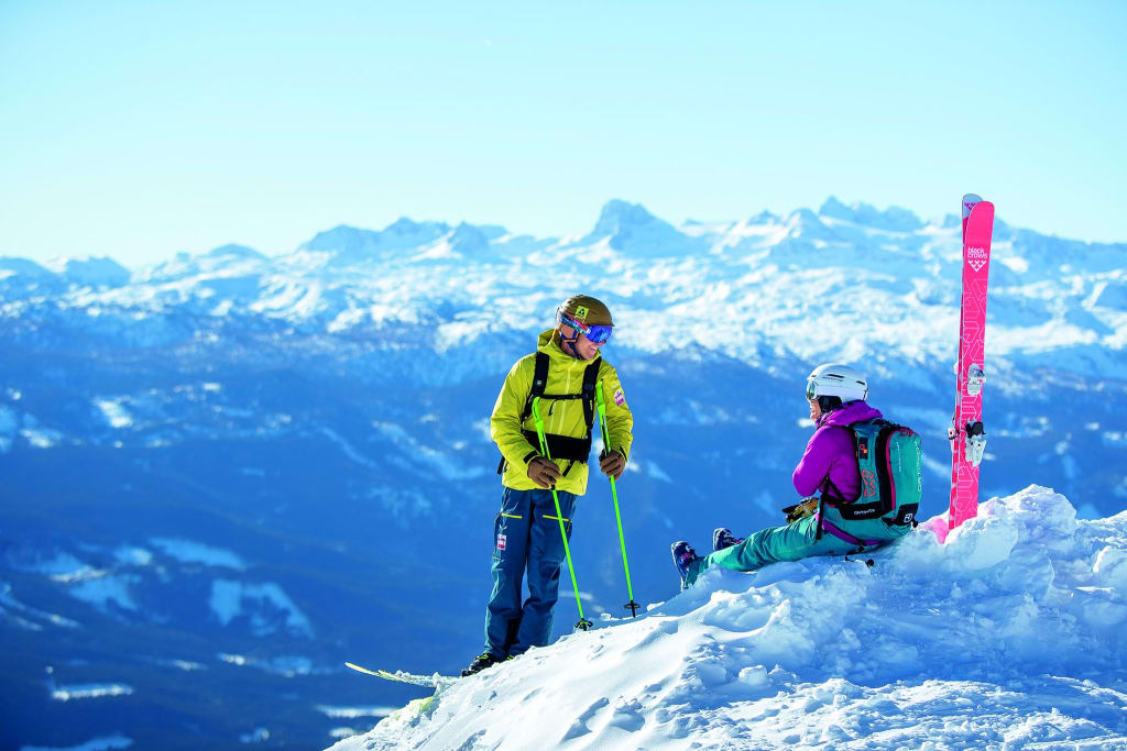 Zwei Skifahrer auf schneebedecktem Berg mit Alpenpanorama