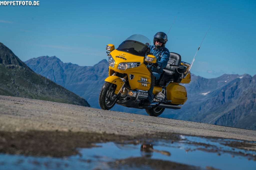 Volltreffer für Biker Mann fährt Motorradtour auf gelbem Motorrad in den Bergen