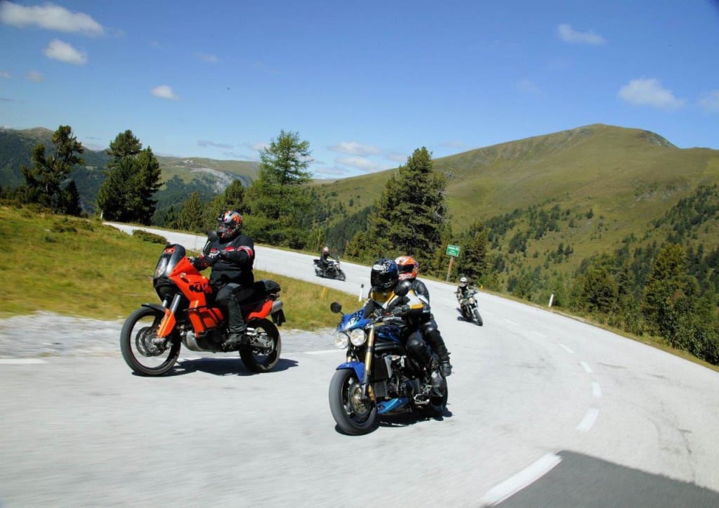 Motorradfahrer fahren auf kurviger Bergstraße bei sonnigem Wetter