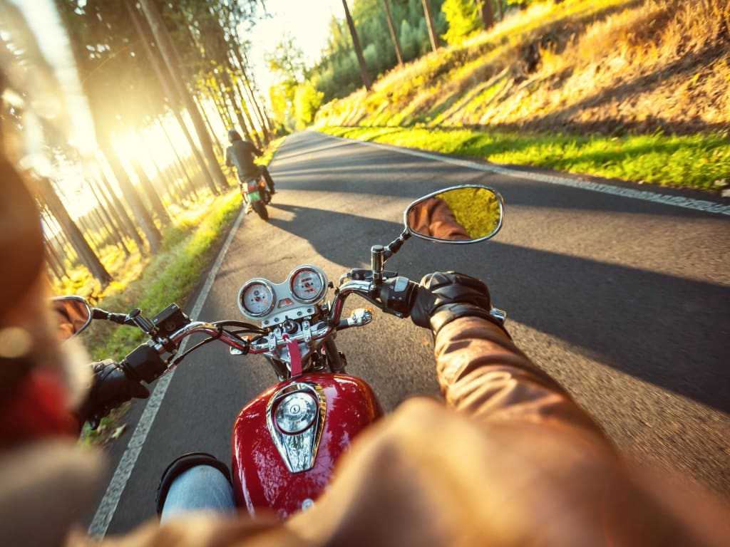 Dolomiti Motorbike Days Motorradfahrer fährt auf Landstraße im Sonnenlicht