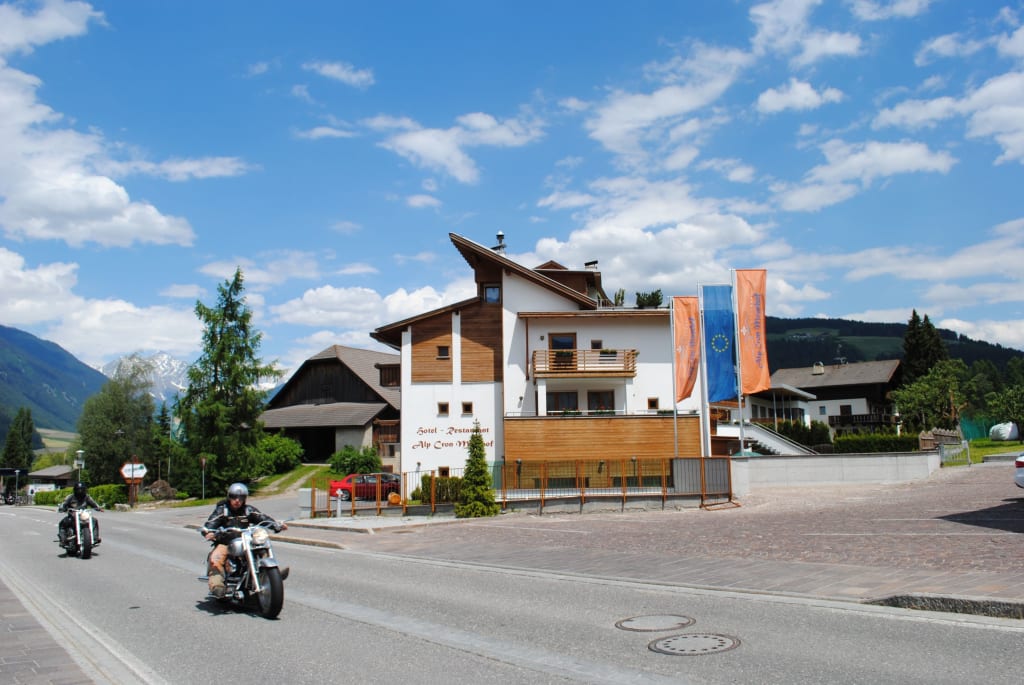 Moar's Bike & Relax Week Straße mit Motorrädern vor einem Hotel in einer Alpenlandschaft