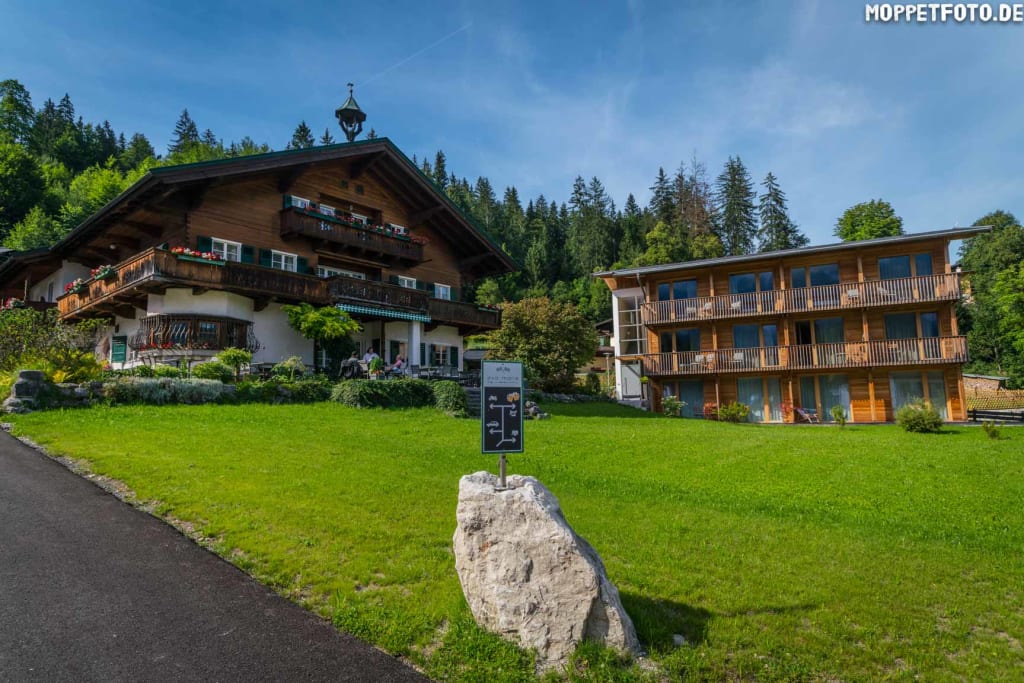 Traditionelles Holzhaus neben modernem Holzhaus in grüner Landschaft