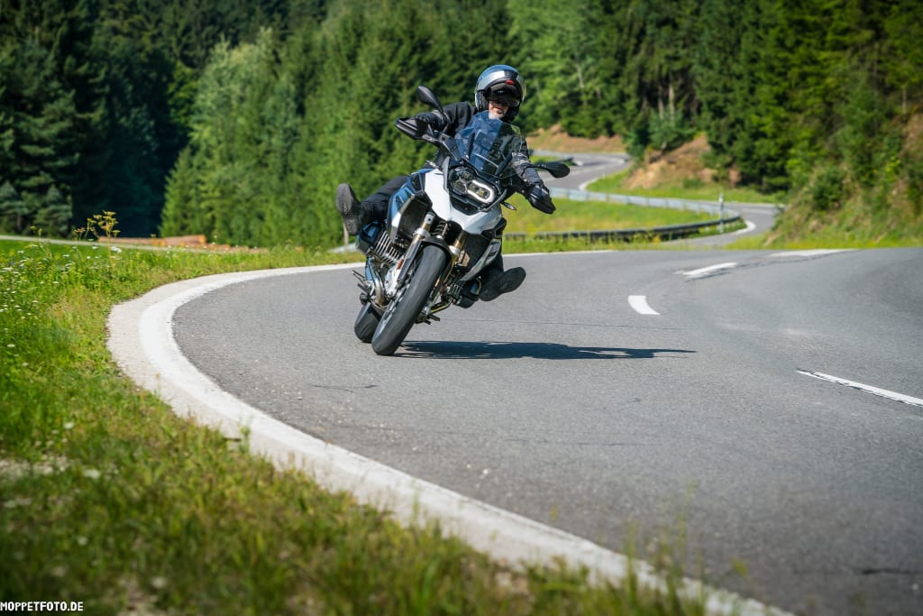 Motorradfahrer in voller Schutzkleidung auf kurviger Bergstraße