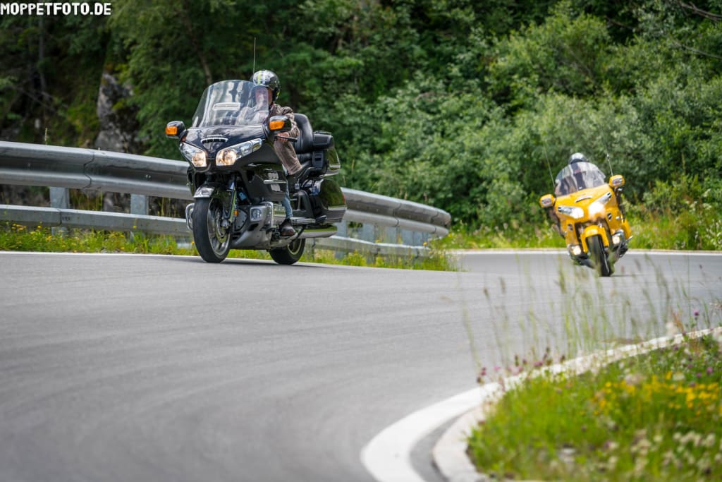 Tourenjagd der 1.000 Möglichkeiten für Biker Zwei Motorräder fahren auf einer kurvigen Straße mit Grünflächen