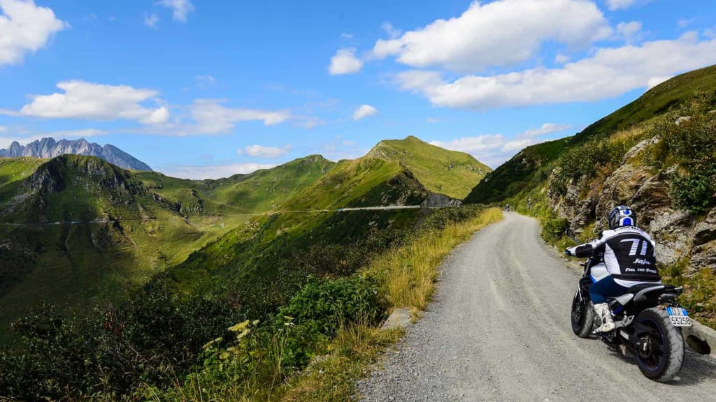 Motorrad-Emotion mit Genuss Motorradfahrer auf Bergstraße mit grünen Bergen und blauem Himmel