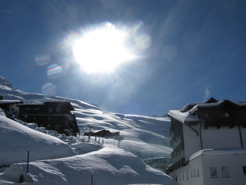 Sonnenschilauf-Pauschale Sonniger Wintertag mit verschneiten Häusern und Bergen