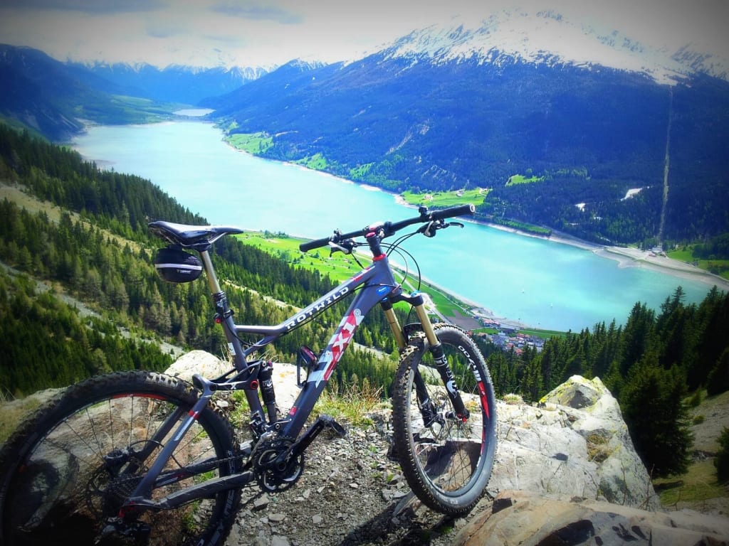 Mountainbike auf Felsen mit Blick auf See und Berge