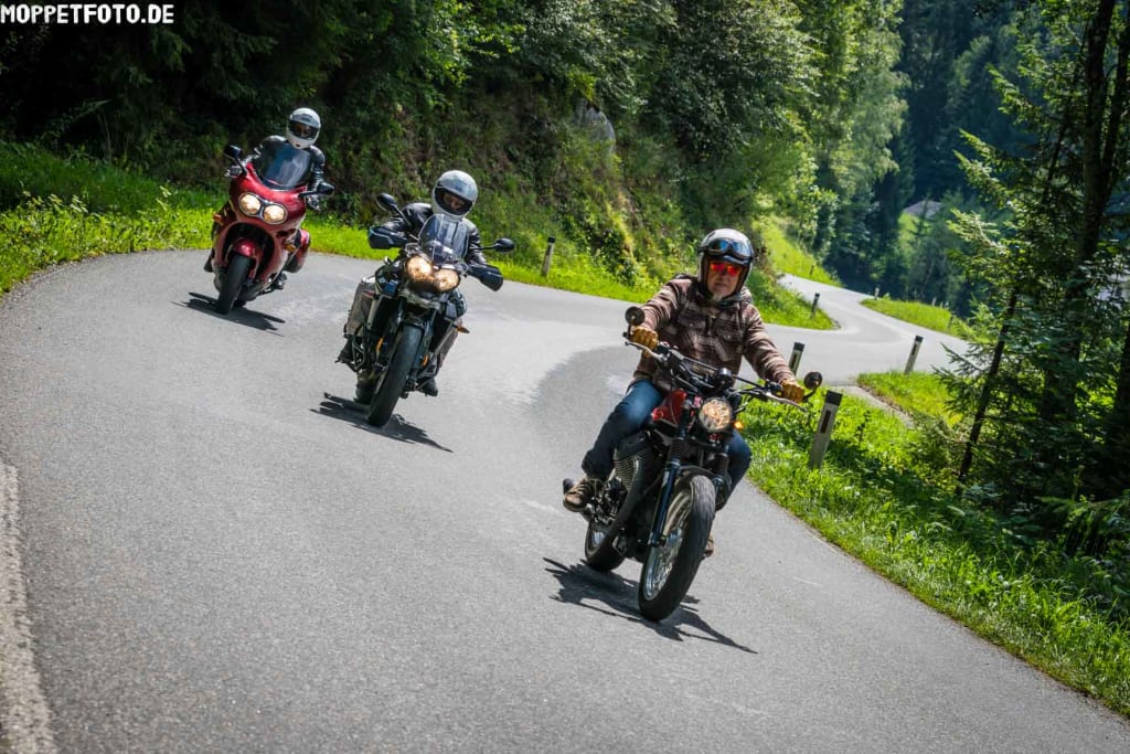 Drei Motorradfahrer fahren auf kurviger Waldstraße