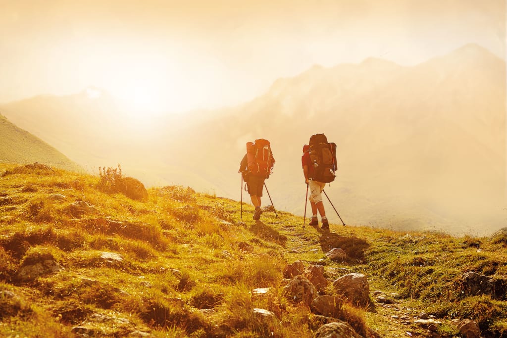 Aktivurlaub für Erlebnissammler - 7 Nächte Zwei Wanderer mit Rucksäcken wandern auf einem sonnigen Bergweg