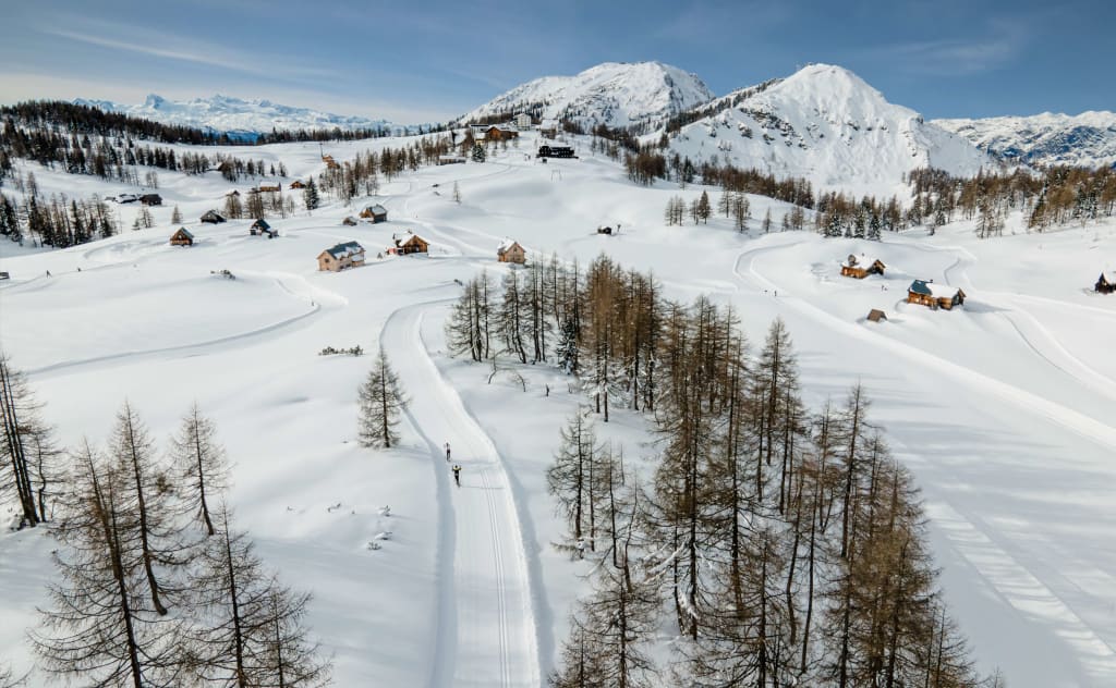 Schneebedeckte Berge mit verstreuten Häusern und Nadelbäumen im Winter
